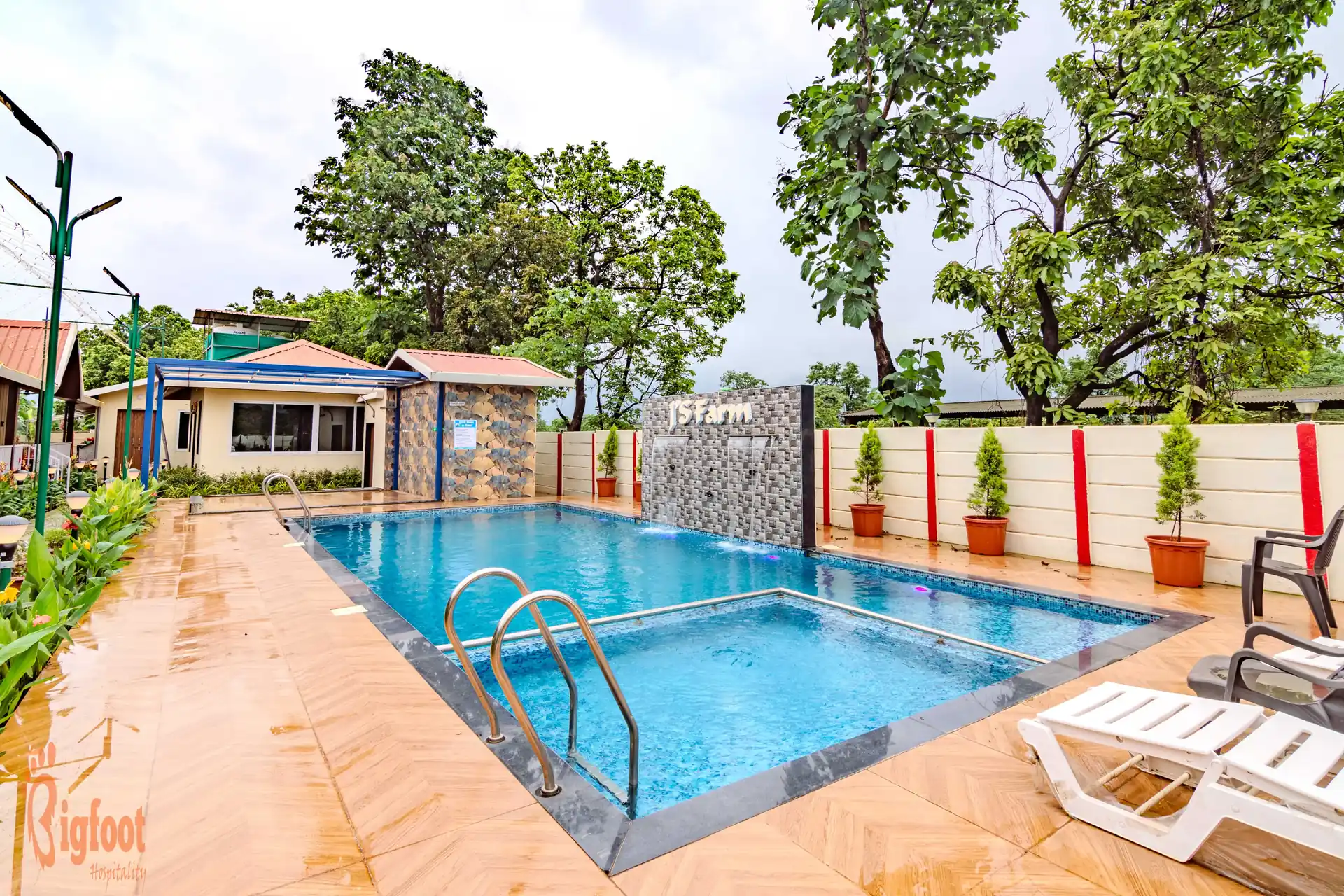 Swimming pool surrounded by greenery at JS Farm Resort, Karjat